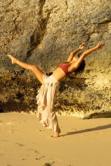 piera on a golden beach doing a yoga standing pose