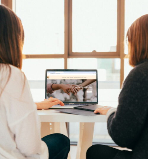 person sitting with student at computer mentoring